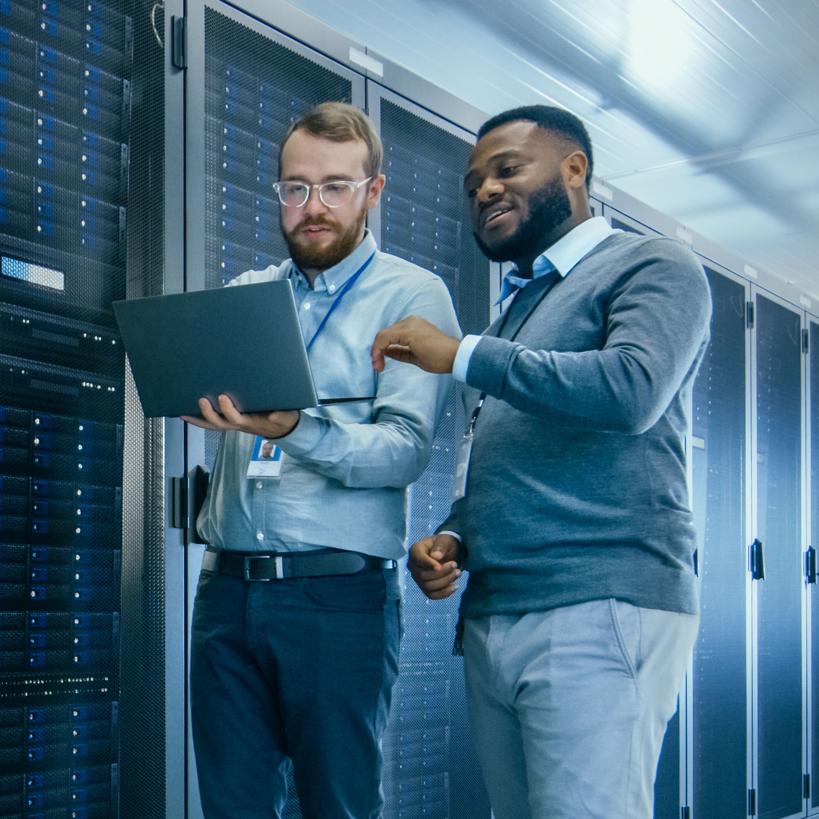 Two male coworkers looking at a laptop in a data center