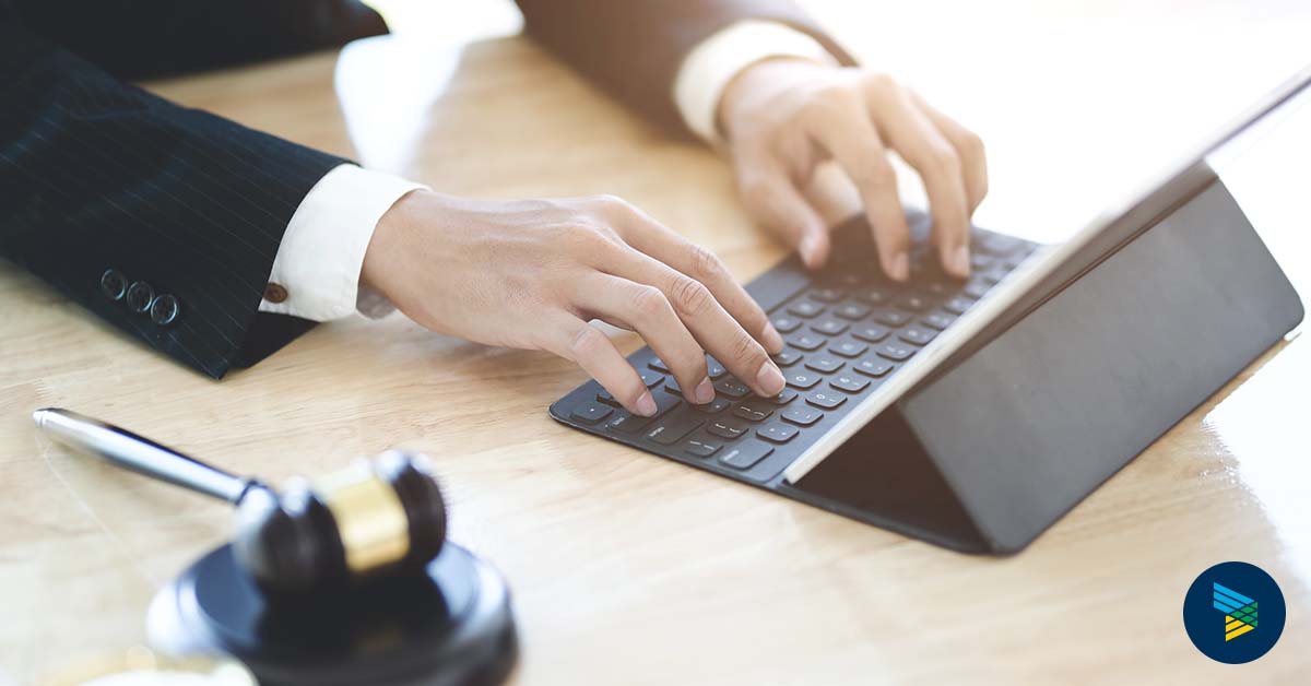 Man typing on a keyboard at a desk with a gavel on it